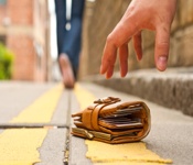 hand reaching for a wallet on the ground as person walks away