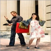 woman with shopping bags next to husband calculating costs